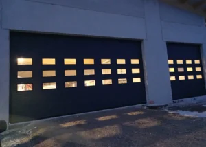 Zwei große Deckensektionaltore in dunkler Farbe, jeweils mit mehreren rechteckigen Fenstern versehen