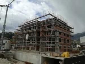 Mehrstöckiges Wohngebäude im Rohbau, vollständig von Gerüsts aus mehreren Plattformen umgeben