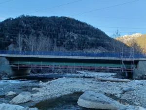 Brücke über einen flachen, steinigen Fluss mit darunter montiertem Hängegerüst