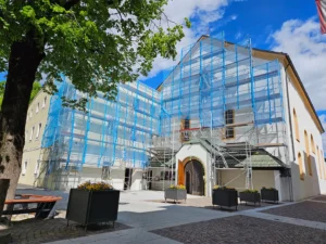 Franziskanerkloster vollständig von einem Baugerüst umgeben, das mit blauem Schutznetz verkleidet ist