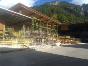 Großes Industriegerüst, umgeben von Baumaterialien und gestapeltem Holz.